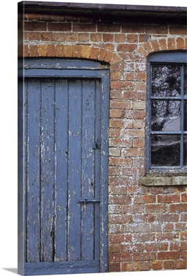 Old orange brick stable block with blue painted wooden door and windows