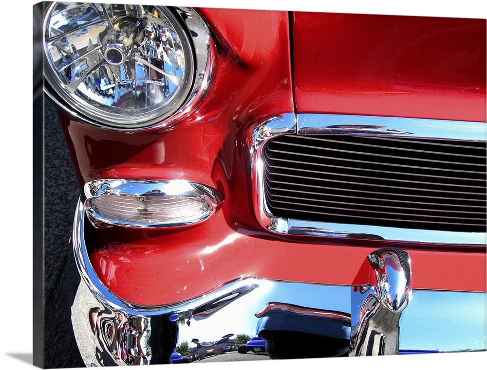 The front of a red car with shiny chrome bumper and grill