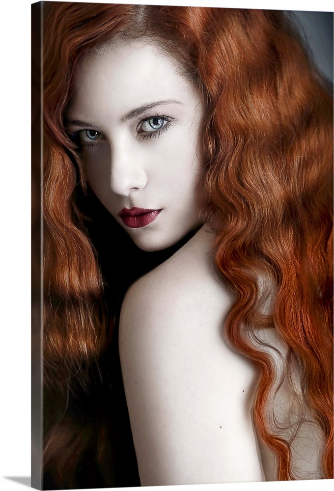A glamorous portrait of a young adult with wavy red hair looking over her shoulder