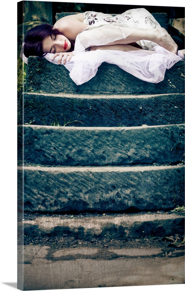Image of a sleeping young woman on the top of a set of stone steps in a peaceful garden setting