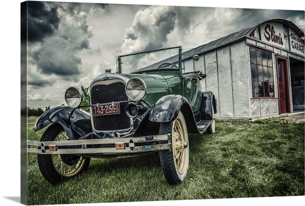 Vintage Model T Ford parked outside tin garage called Slim's on grass under cloudy sky