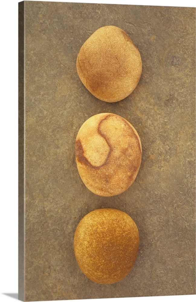 Three smooth brown pebbles lined up on brown stone surface