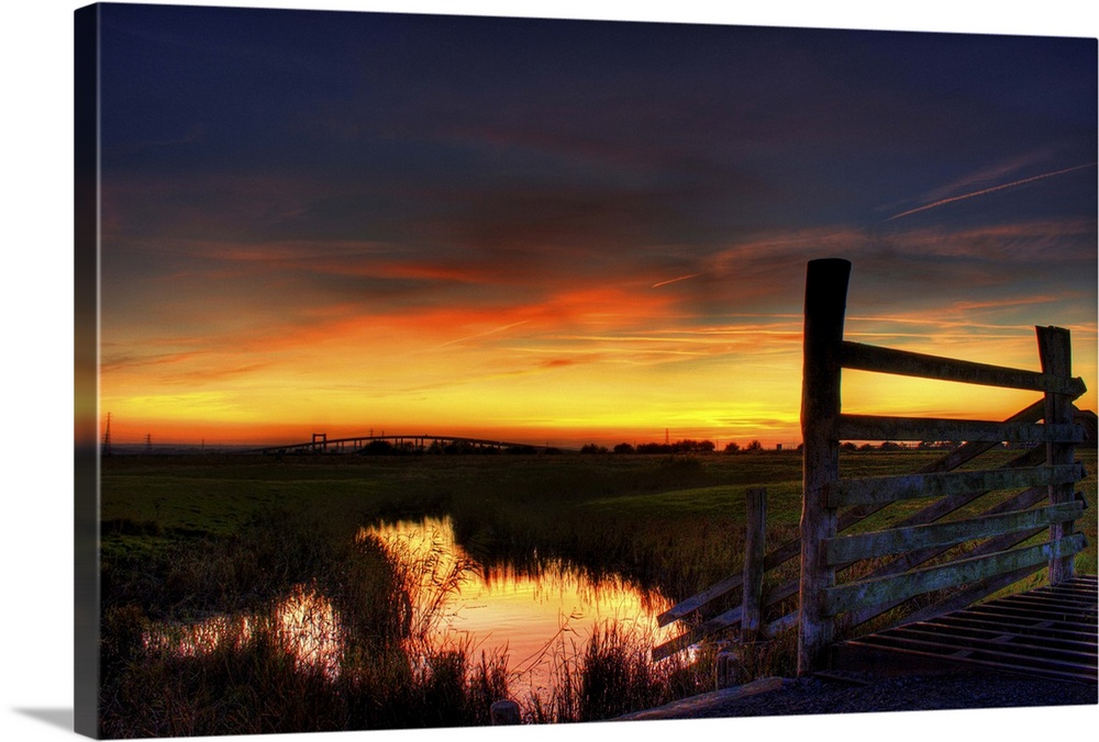 Sunset over Elmley marshes, with the Swale Crossing and Kingsferry Bridge in the background and reflections of the sunset ...