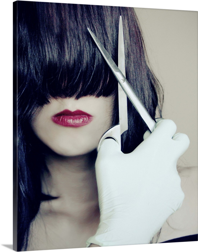 Close-up portrait of a young woman with pale skin and dark hair covering her eyes, holding scissors with a surgical glove ...