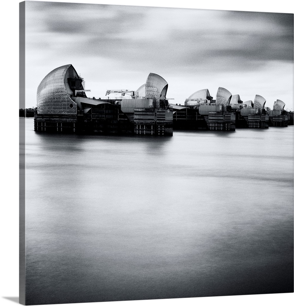 Thames Barrier, london with Canary Wharf in background under grey sky