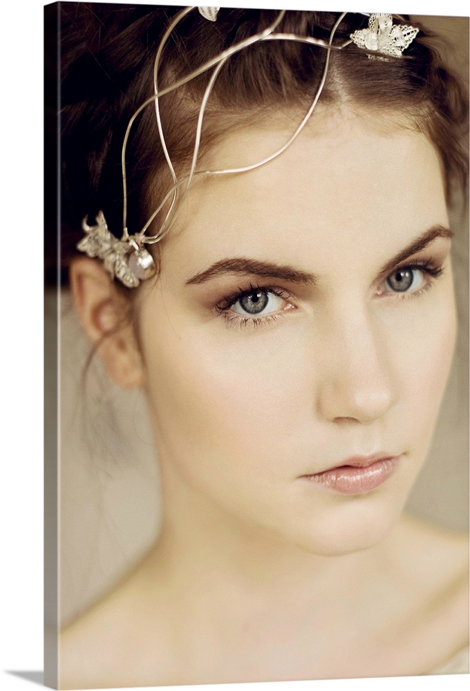 Close portrait of young woman with silver headpiece and braided hair looking into the camera
