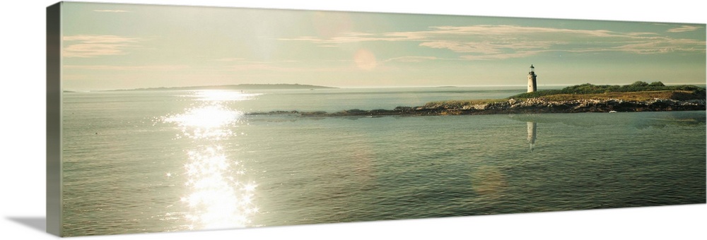 Panoramic photograph of a lighthouse on the sound with the sun shining on the water.