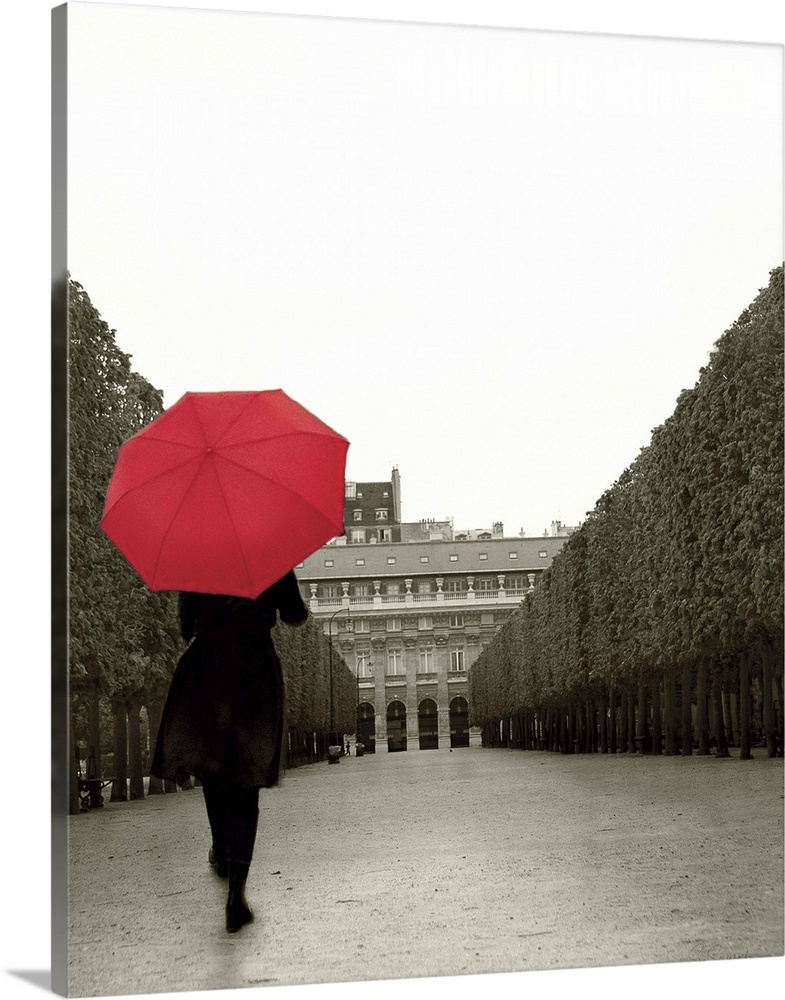 A photograph of a person walking down an empty road with a red umbrella overhead.