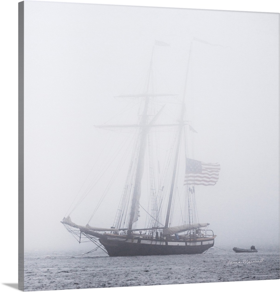 A square photograph of a large sail boat blanketed in a heavy fog.