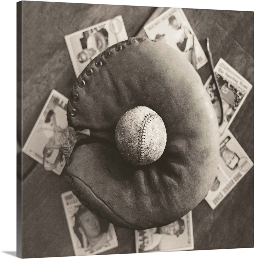 Square sepia toned photograph of a worn baseball in an old mitt and vintage baseball cards behind it.
