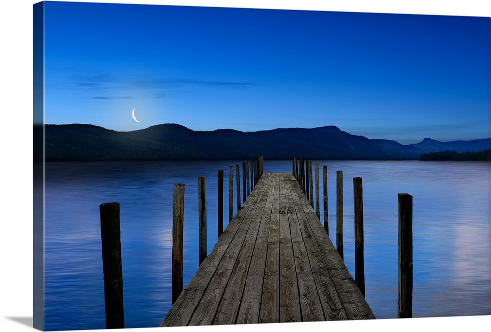 This atmospheric photo features an empty dock reaching out into a serene lake with a crescent moon setting in the background.