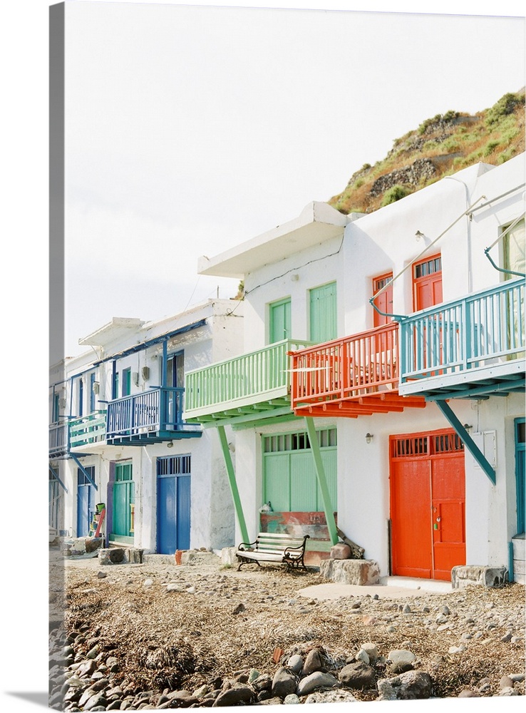 Photograph of beach buildings in Milos, Greece, with colorfully painted doors and balconies.