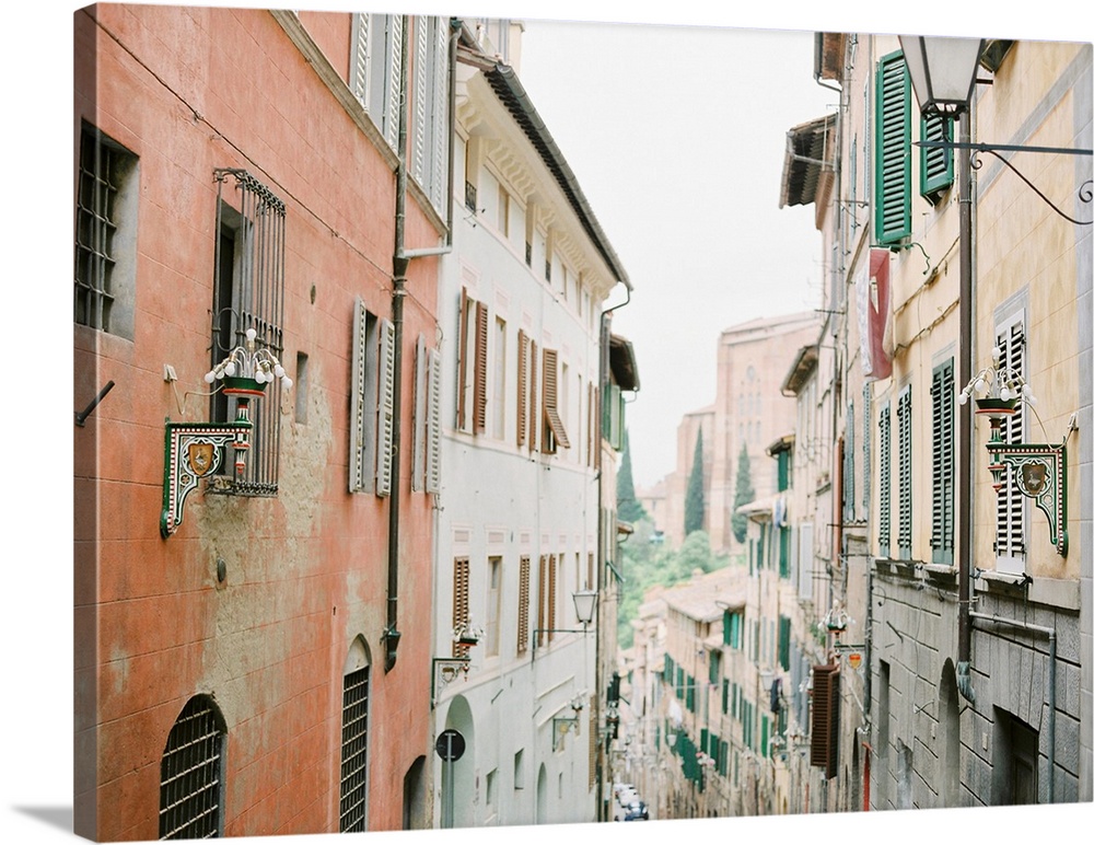 Photograph of a narrow alleyway between two tall buildings adorned with shutters, Italy.