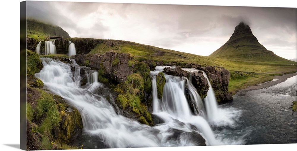 Stormy clouds gather over tranquil waterfalls in this luscious green landscape photograph.