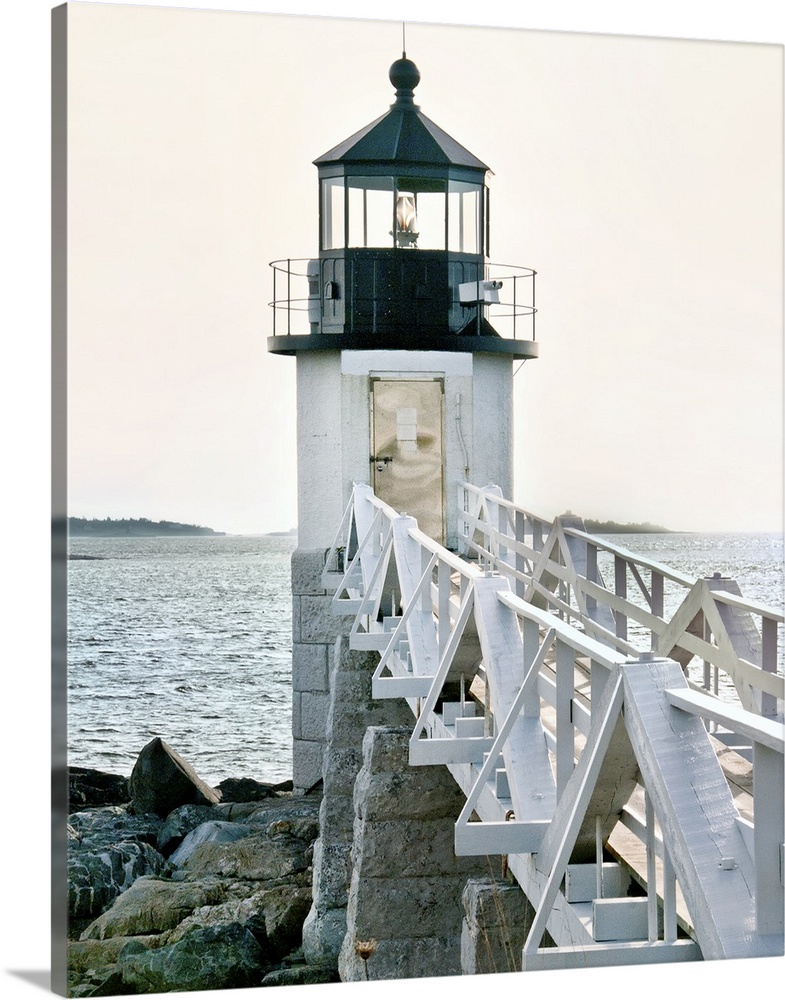 A photograph of a lighthouse at the end of a pier jetting out over the water.