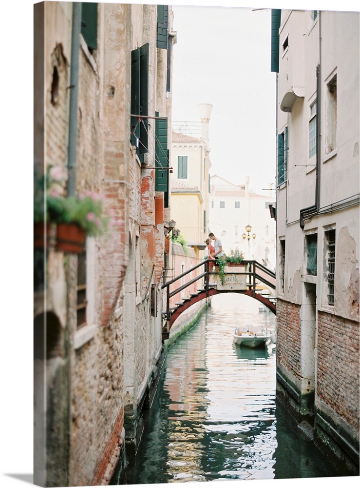 Photograph of a couple kissing on a bridge over a canal, Venice, Italy.