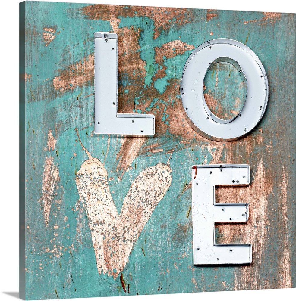 The word "Love" made of metal letters and a painted heart on weathered teal boards.
