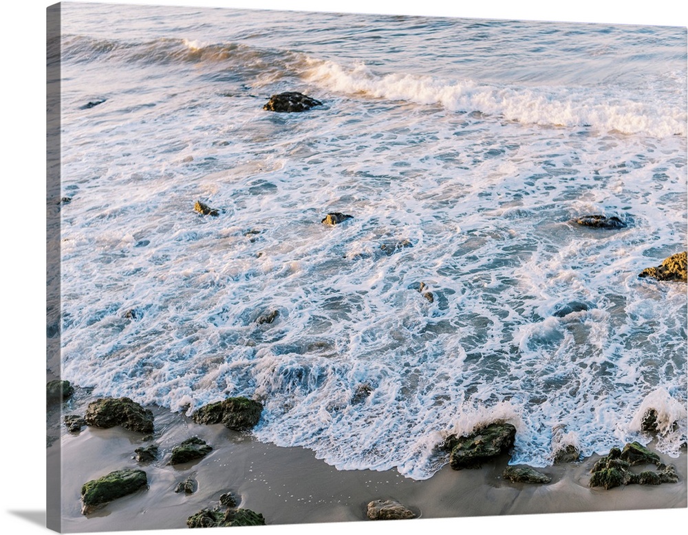 A photograph of gentle waves lapping the beach.