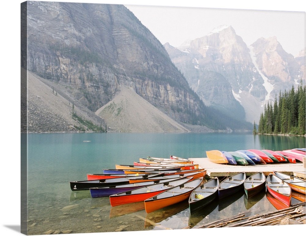 A photograph of colorful canoes on the edge of Moraine Lake, Banff National Park, Alberta, Canada.