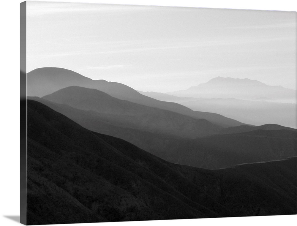 A black and white photograph of a landscape of a silhouetted mountainous valley.