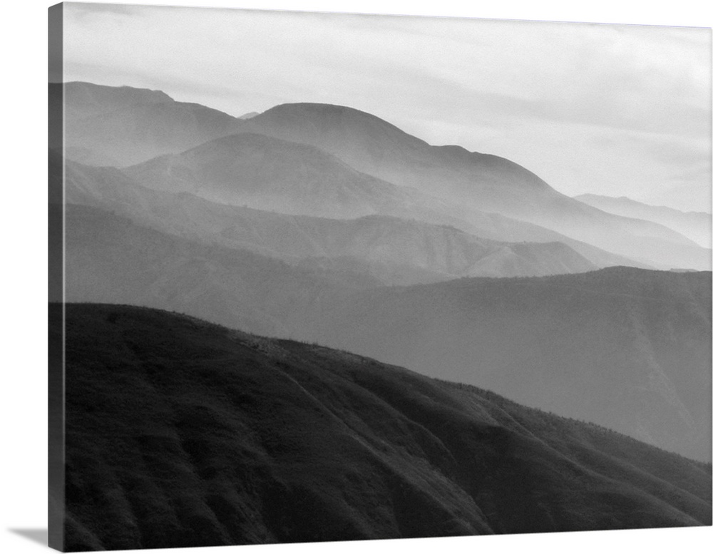 A black and white photograph of a landscape of a silhouetted mountainous valley.