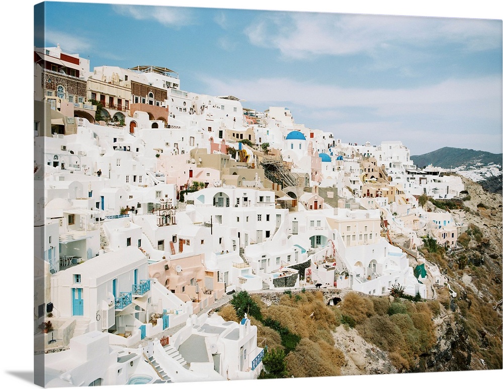 Photograph of the iconic white buildings of Santorini, Greece perched on the hillside.