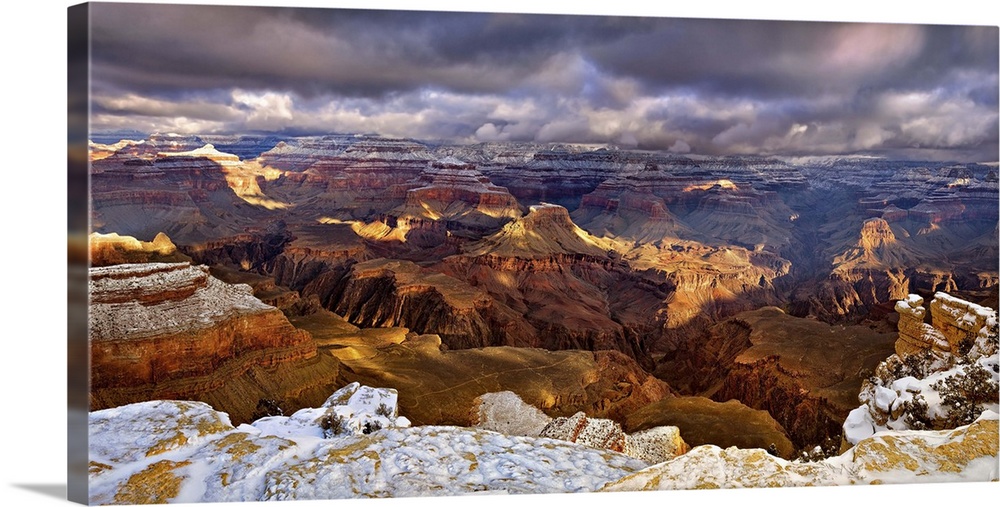 Vista of the Grand Canyon in Arizona under a blanket of snow and dark storm clouds.