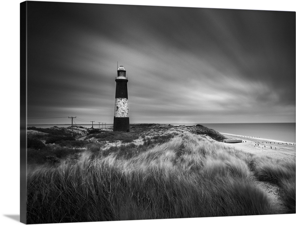 Fine art photo of a striped lighthouse on the coast near grassy dunes.