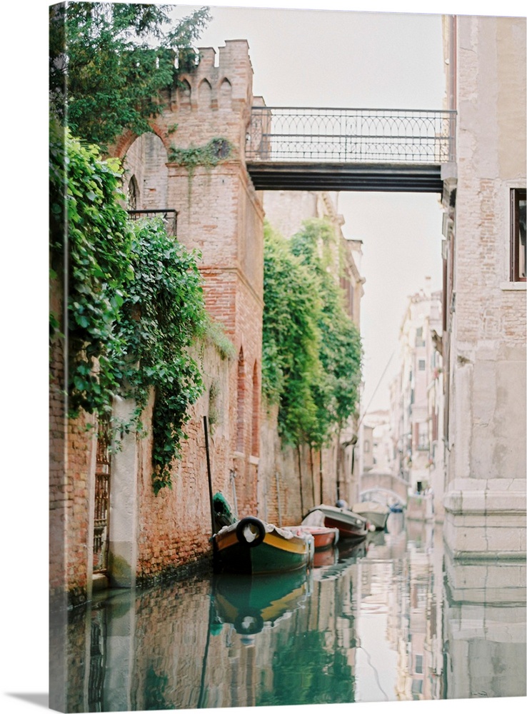 Photograph of small boats moored beneath an old brick wall, Venice, Italy.