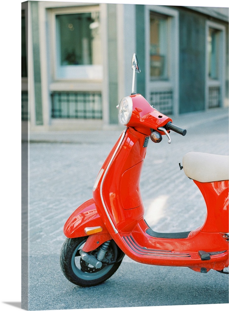 A photograph of a red scooter parked on the street.