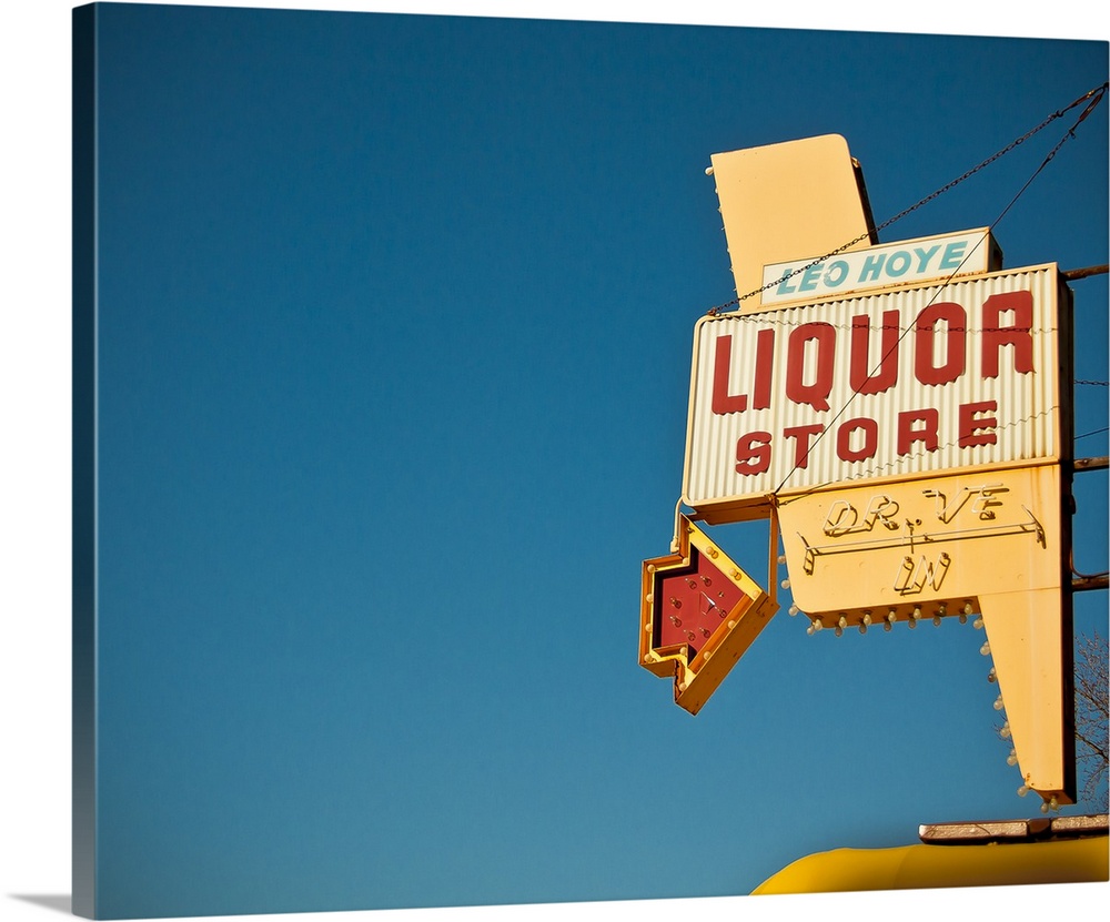 Photograph of mid-century liquor store sign against a blue sky.