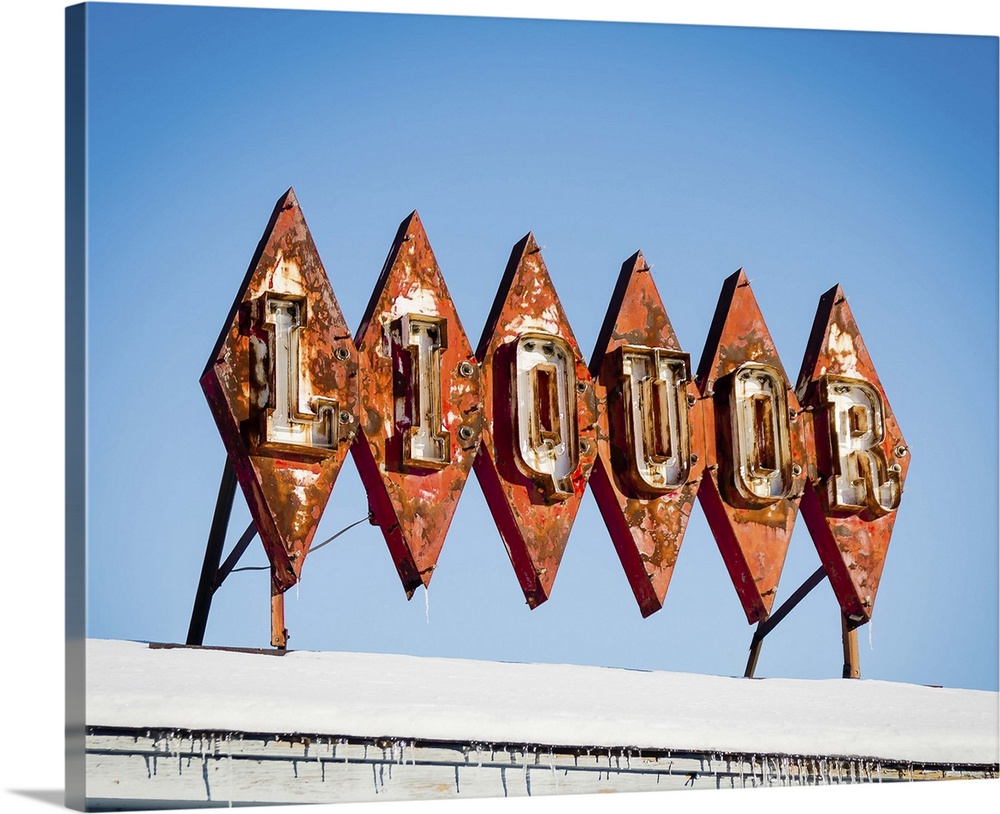 Photograph of mid-century liquor store sign against a blue sky.