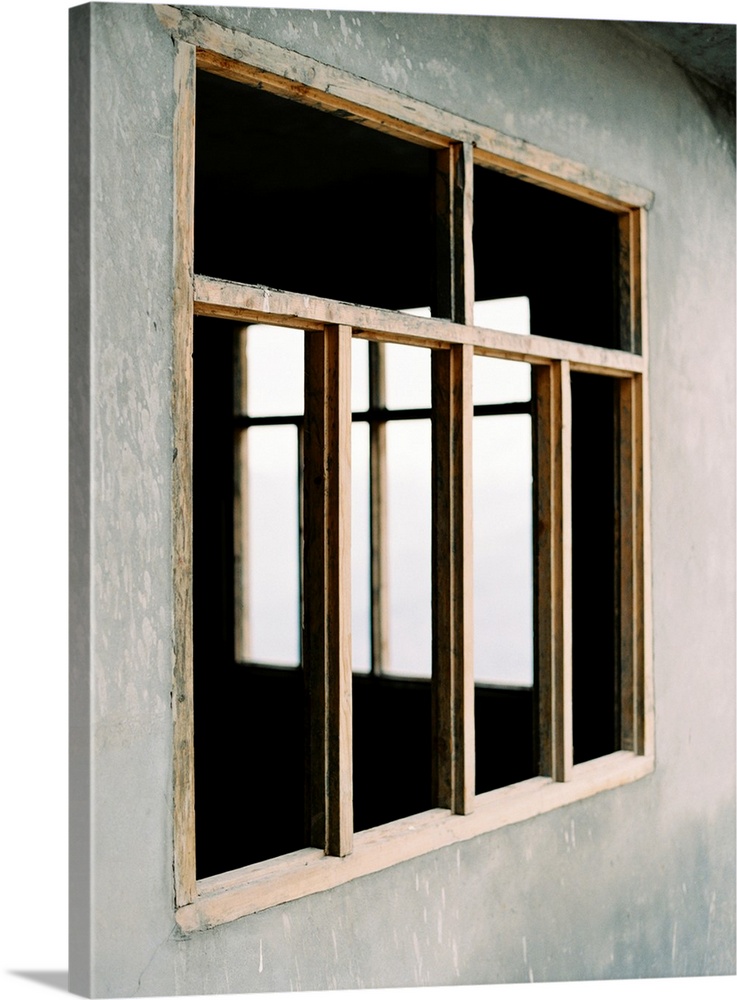 A poetic photograph of simple wooden window frames in a stucco wall.