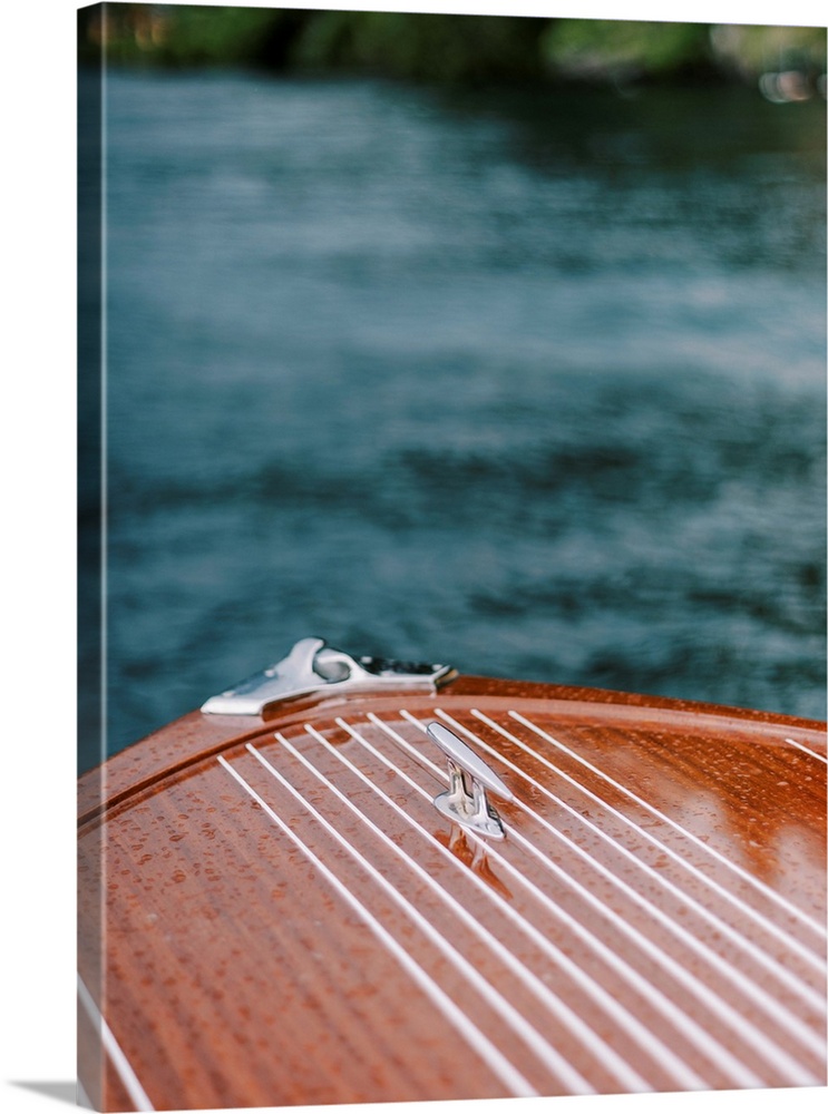 A photograph of the bow of a beautiful wooden motorboat on the water.